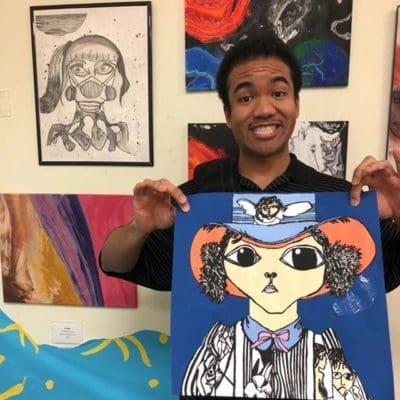 young man at OSBI holding up his artwork