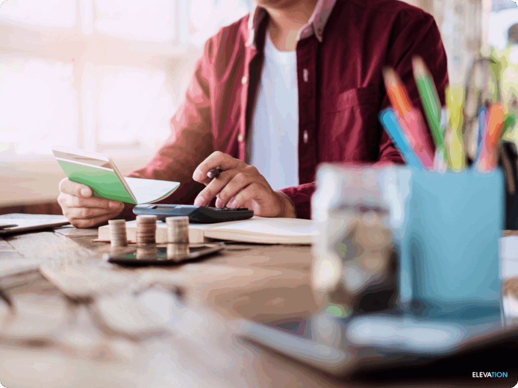 Male at desk using calculator and checkbook