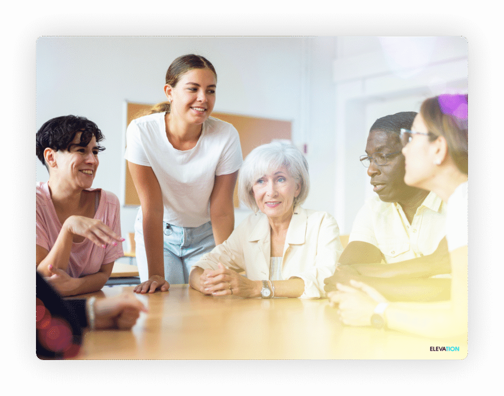 Group of people of all ages sitting around an office table